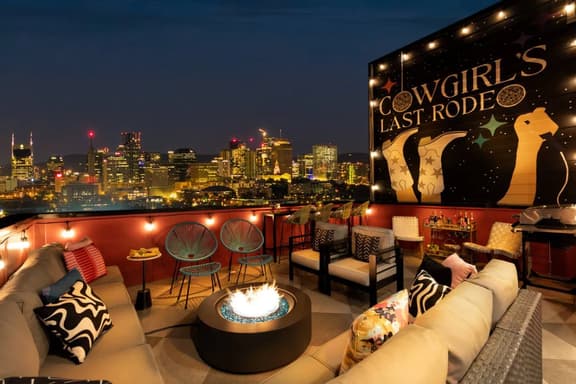 The rooftop balcony offers stunning skyline views, an outdoor sofa, a bar table with stools, and a fire pit. The perfect spot to unwind, enjoy a drink and take in the cityscape!